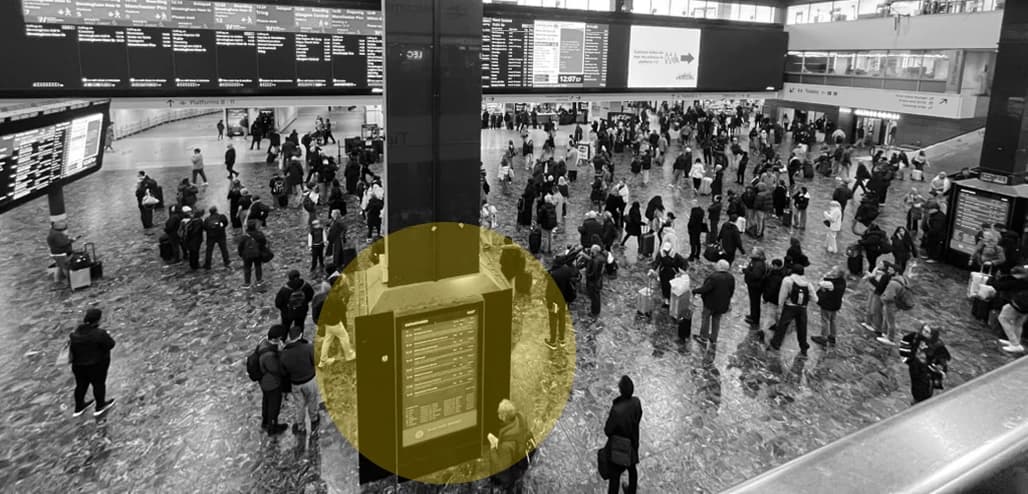 Stationary travellers repeatedly looking up at screens and down at their phones.